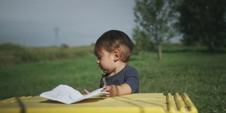 Toddler drawing at an outdoor table in a garden
