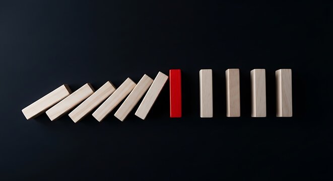 Wooden blocks, dominoes, toppling on a dark surface, one red block standing