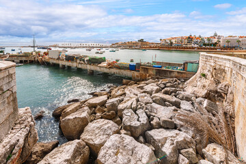 Fototapeta premium The rocky coastline along the scenic bay and marina of Cascais, Portugal, a historic fishing town turned popular seaside resort along the Portuguese Riviera.