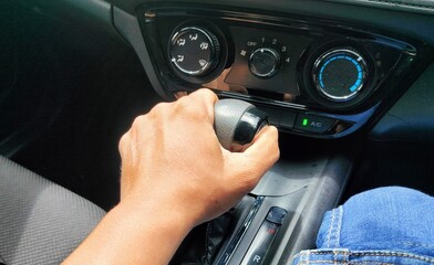 Naklejka premium how to enter car gear by pressing the button. driving a car. hand of man on gear auto in car. hand changing gear while driving car.