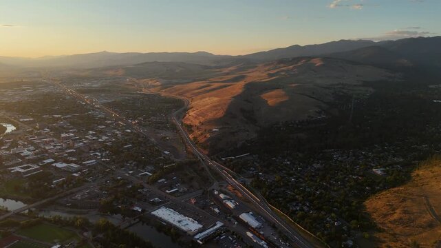 Wider aerial view of Missoula, Montana and Interstate 90 highway corridor at sunset 4K drone video