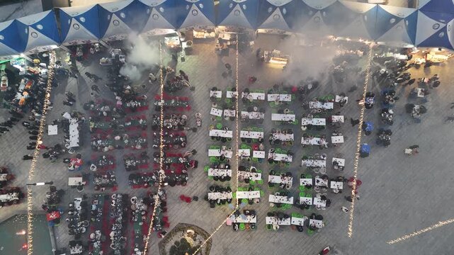 Aerial view captures hundreds of Muslims gathered at long tables for a communal Iftar meal at Ramadan.