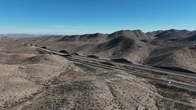Aerial drone video in 4K of vehicles and semi-trucks driving on an interstate highway through the desert landscape in West Texas