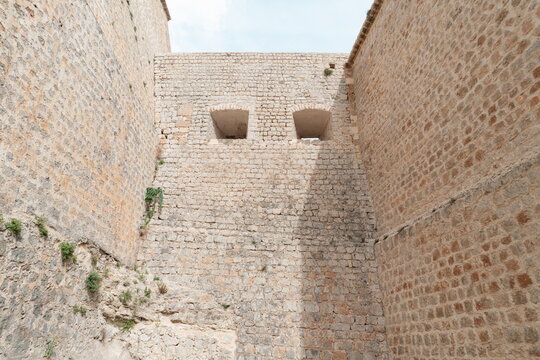 Massive stone fortress walls with embrasures in castle, Ibiza Spain