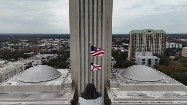 American and Florida state flags flying outside the Capitol tower in Tallahassee, 4K aerial drone view