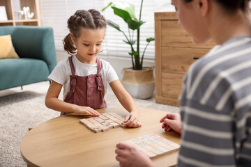 Fototapeta premium Mother and her daughter playing with educational toys at wooden table indoors, closeup