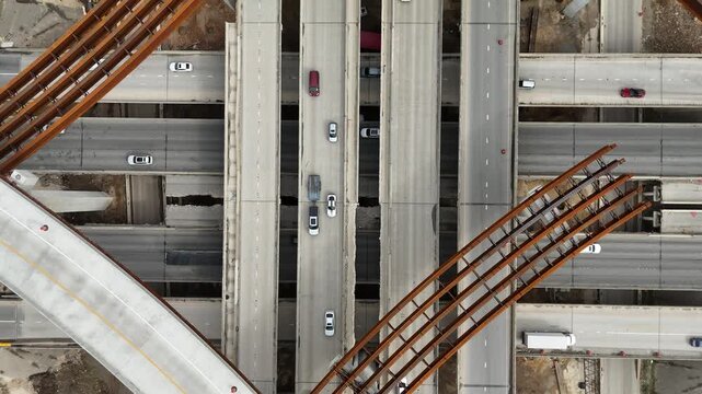 Highway intersection and multi-level bridge construction project with steel beams spanning over busy Texas traffic lanes 4k aerial drone video