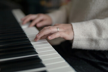 Fototapeta premium Woman playing piano, close up of hands on piano keys, music practice and creativity