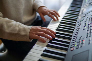 Obraz premium Woman playing piano, close up of hands on piano keys, music practice and creativity