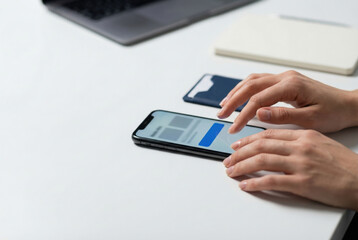 Fototapeta premium Woman touching screen of smartphone on office desk. Female hand using mobile device for online communication and work. Digital business technology and modern professional connectivity concept.