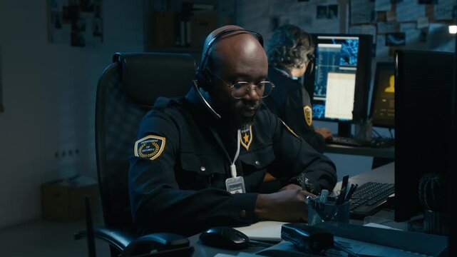 Dramatic shot of African American man as police dispatcher taking emergency call speaking into headset and getting emotional when connection breaks, hitting desk