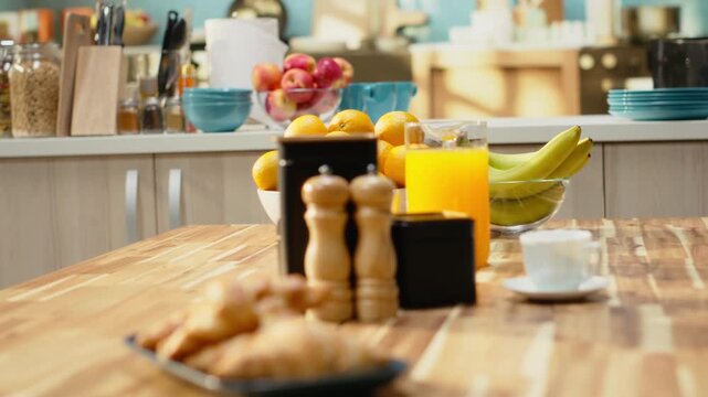 Kitchen interior with croissants and coffee for breakfast meal. Warm tones and natural light in empty home interior. Wooden table and kitchenware creates modern atmosphere with no people indoors.