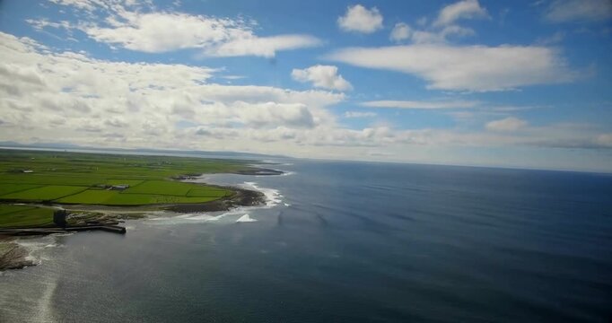 Drone panning coastline, signal glitching then clearing, revealing harbor, fields, surf for tech