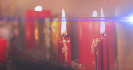 Flickering two red taper candles showing melted wax drips on glass tray at home, blue flare