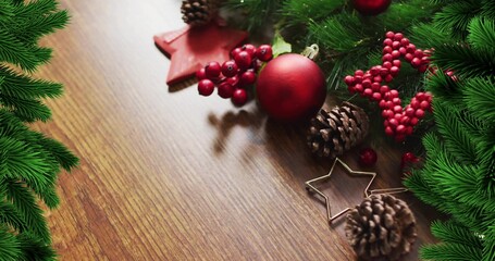 Showing decor cluster resting on wood table, featuring matte red bauble, red berries, cones, fir