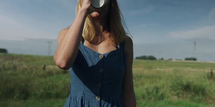 Woman holding a coffee cup in a countryside meadow