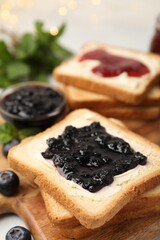 Toasts with butter, sweet jams, blueberries and mint on table, closeup