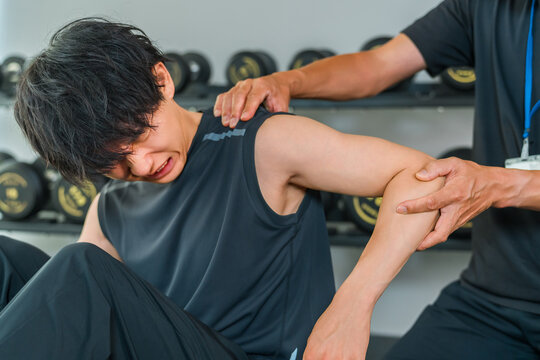 A man experiencing shoulder pain during training and a male sports physical therapist.