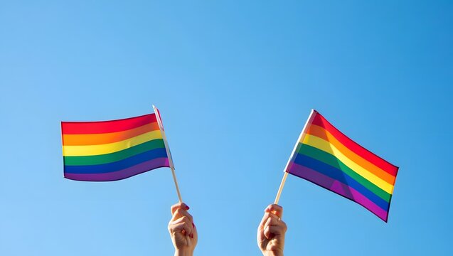 Hands Holding Rainbow Flags Against Clear Blue Sky Background