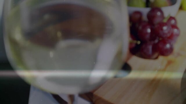Vertical video: Stemmed glass entering left front moving closer, refracting light, softening grapes