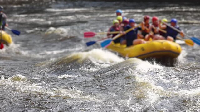Rafting in whitewater, extreme water sports on water rapids, kayaking and canoeing tour in a mountain river,  water sports team, red and yellow raft boat full of tourists in a summer day, slow motion