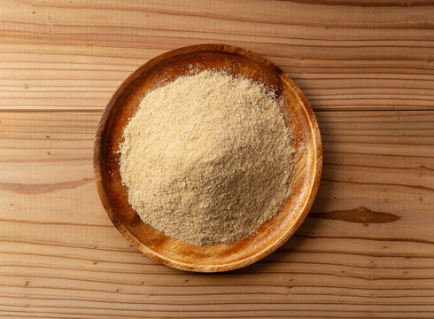 Top view of fresh rice bran powder in a wooden plate on a wooden table
