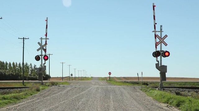 Rail crossing with sound of train coming. Gates lowering. Manitoba. HD.