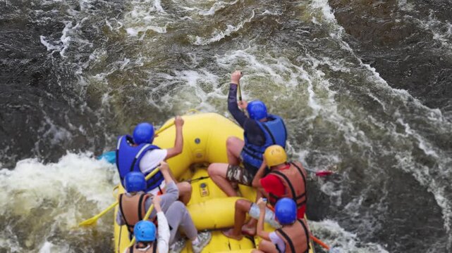 Rafting in whitewater, extreme water sports on water rapids, kayaking and canoeing tour in a mountain river,  water sports team, red and yellow raft boat full of tourists in a summer day, slow motion