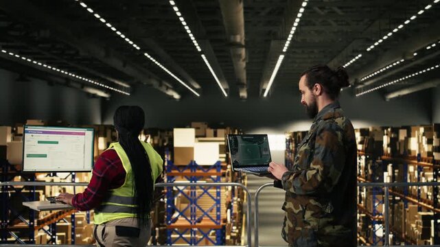 Armed forces engaged in military surveillance using drone monitoring software inside a warehouse storage center. Personnel ensuring defense operations, command and control infrastructure.