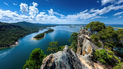 Fototapeta premium Breathtaking Aerial View of a Serene River Valley Surrounded by Lush Green Forests and Dramatic Clouds Under a Bright Blue Sky