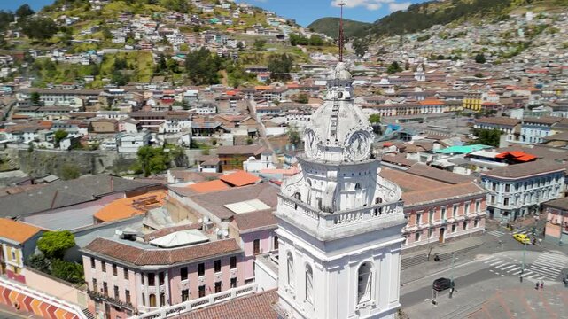 Drone circles and descends over Santo Domingo church baroque clock tower and reveals vast colonial convent courtyard with palm trees in Quito