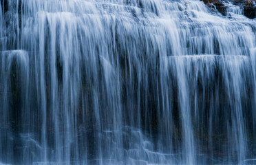 段々のある滝を滑らかな水の流れが白い流れ模様として見られる風景