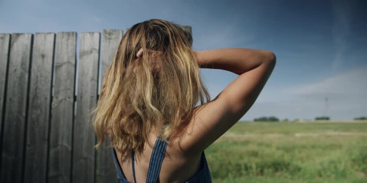 Woman standing by a countryside fence on a summer day