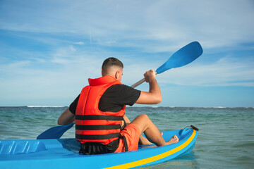 Obraz premium Individual paddling a kayak on calm water enjoying the sunshine