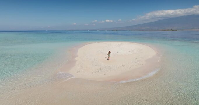 Woman relax on pristine white sandbar beach with clear turquoise water in the scenic Gili Islands, experiencing summer travel vacation and tranquility in this serene tropical paradise. Aerial flight
