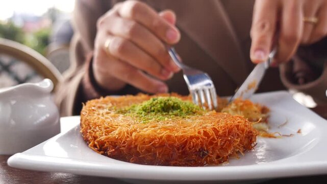 Close-up of Hands Cutting and Eating Traditional Turkish Kunefe Dessert