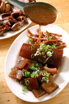 Braised pork skin is a traditional Taiwanese snack; the chef is drizzling the sauce over it.