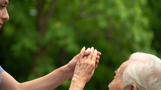 女性介護士が高齢者の手を優しく握り安心を伝える介護サポートシーン。
深いマットグリーンのスタジオ背景と柔らかな光が落ち着いた医療福祉の雰囲気を演出。