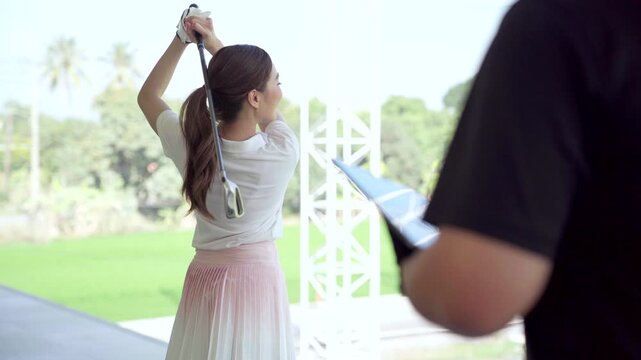 Golf instructor reviewing launch monitor swing data with female golfer at driving range