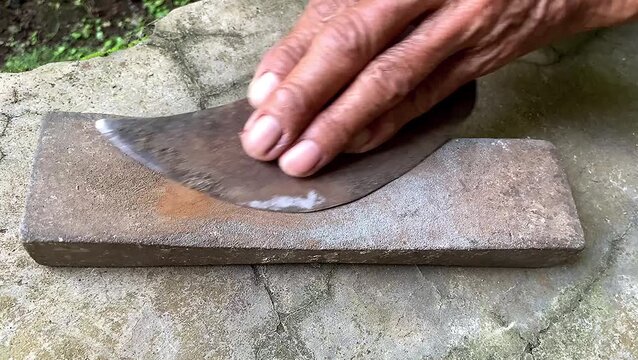 Senior hands sharpening traditional knife on grinding stone. manual labor activity.