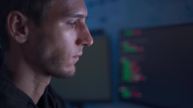 Software developer working at computer with headset in dark office coding environment