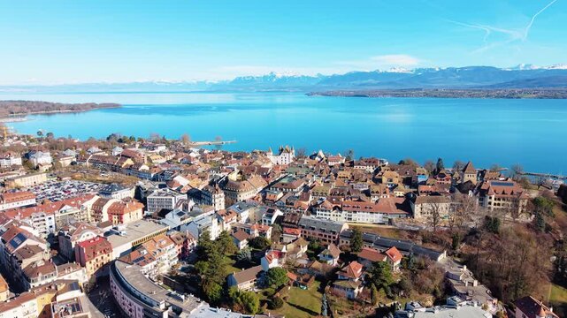 Aerial: Nyon cityscape and downtown during the day with Lake Geneva in Canton of Vaud, Switzerland, orbit drone shot