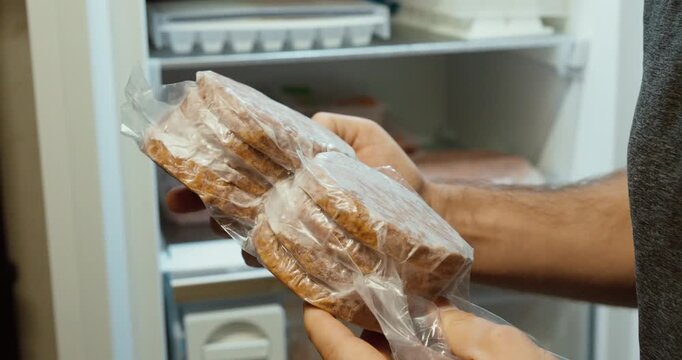 frozen hamburger patties being placed into a freezer. Concept of food storage, freezing meat, meal preparation, and household kitchen organization.