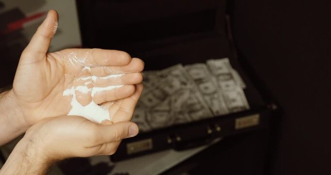hands holding white powder with a briefcase full of cash in the background. Concept of illegal drugs, narcotics trade, crime money, and underground economy.
