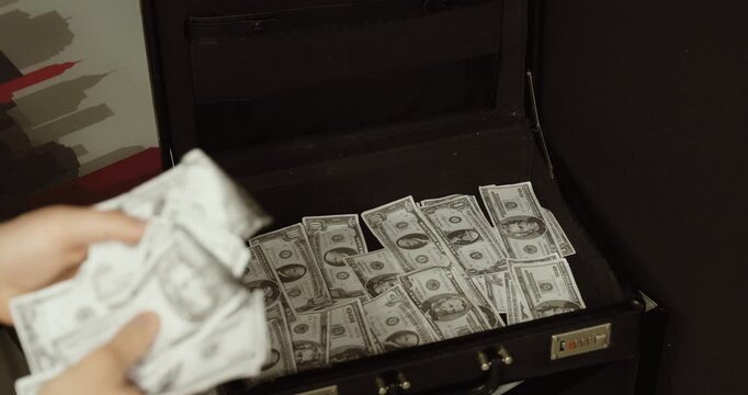 Close-up of hands counting banknotes in front of an open briefcase filled with cash. Concept of wealth, financial transactions, business deals, corruption, and large amounts of money.