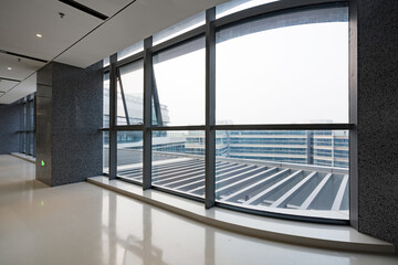 Naklejka premium Modern office interior with curved floor-to-ceiling windows offering urban landscape view