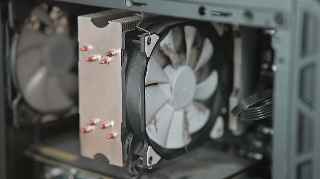 Close-up view of dusty and dirty fan computer cooling fan being installed in a case.