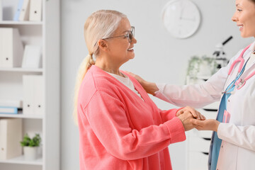 Obraz premium Mature woman with gynecologist holding hands in clinic. Menopause concept