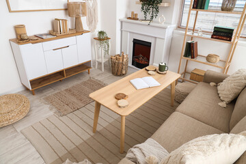 Naklejka premium Interior of living room with sofa, shelving unit, coffee table, fireplace, commode and firewood in wicker basket, top view