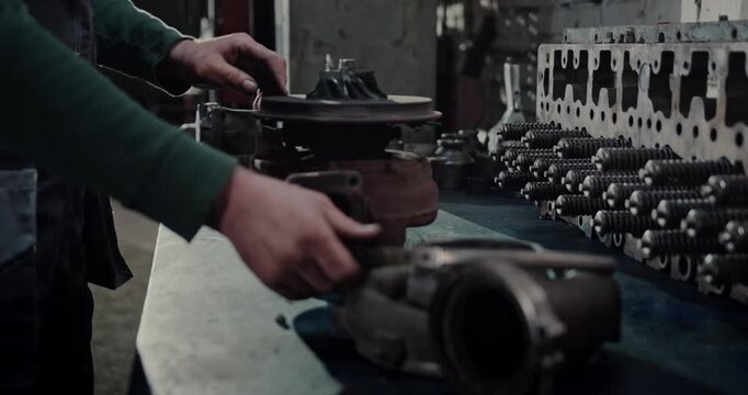 mechanic examining turbocharger turbine and cylinder head in garage